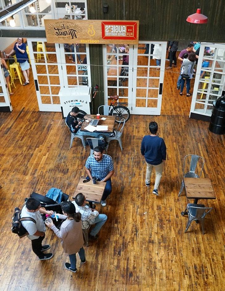 groups of people sit at tables outside augie's cafe in the claremont packing house